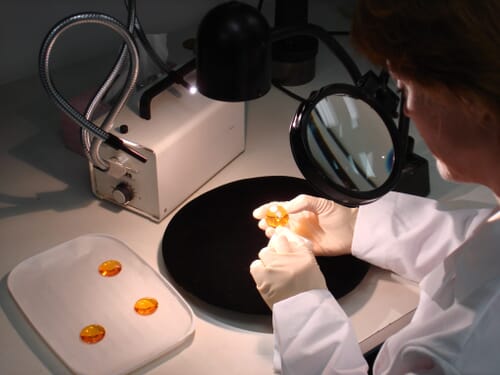 Lab technician inspecting orange-tinted lenses under magnification