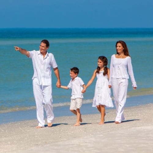 Wealthy family dressed in white walking on the beach