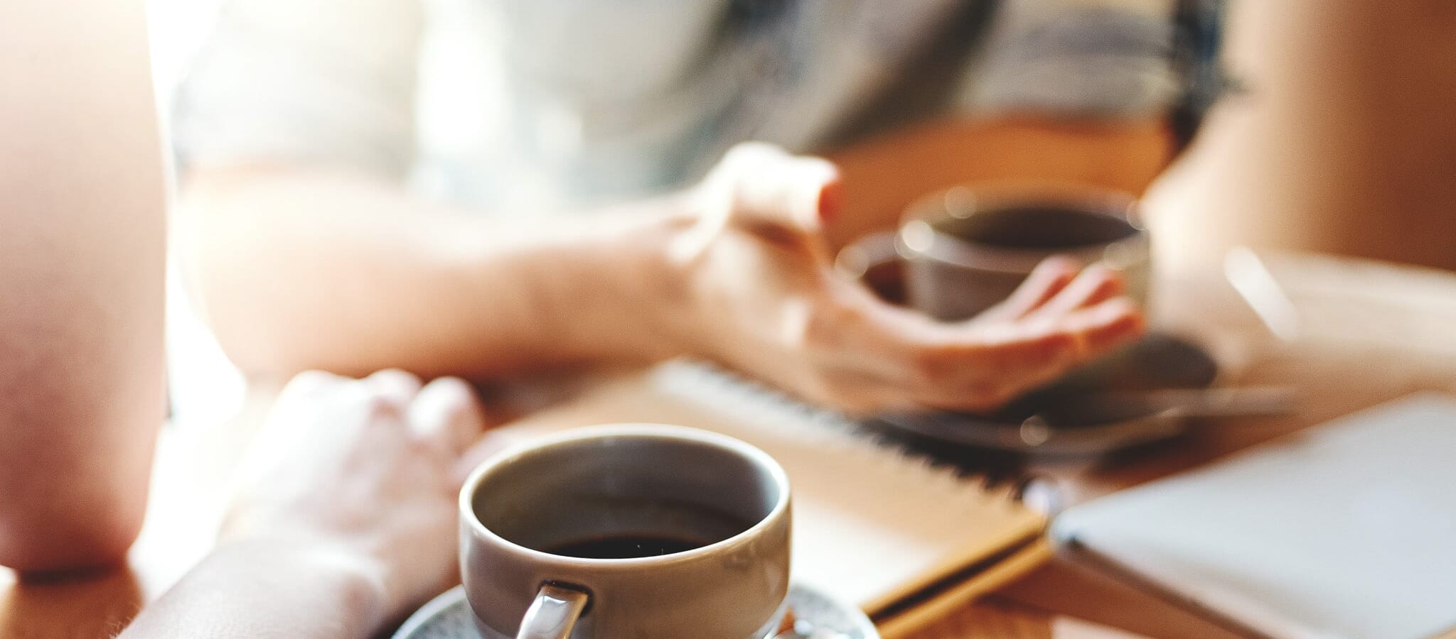 Hands and cups of two people talking at a coffee shop