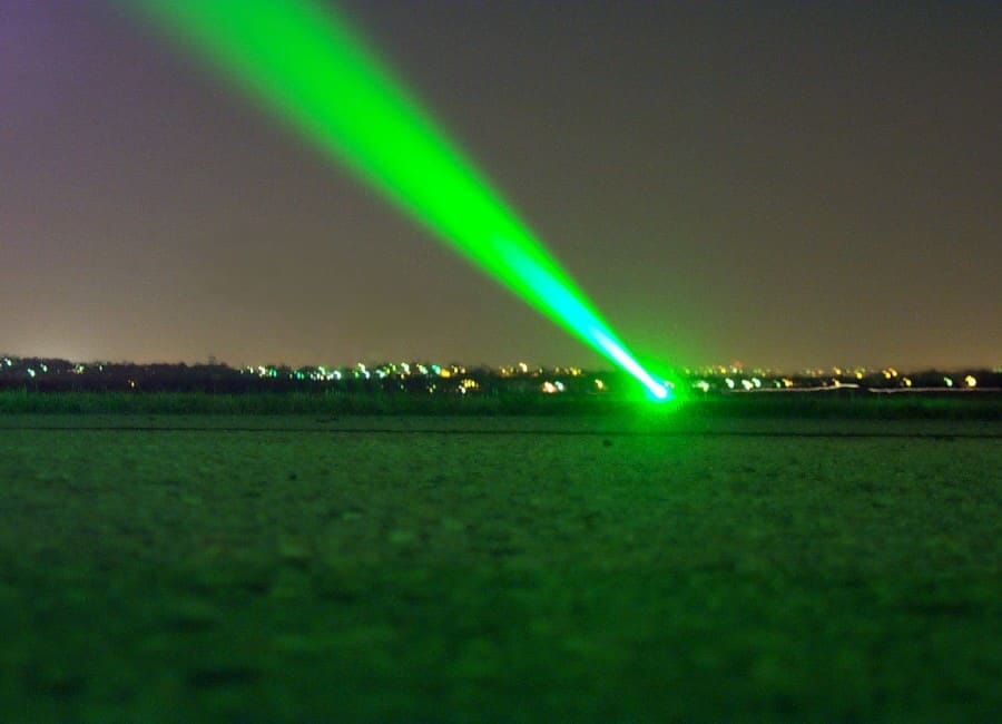 Green laser beam across a field at night