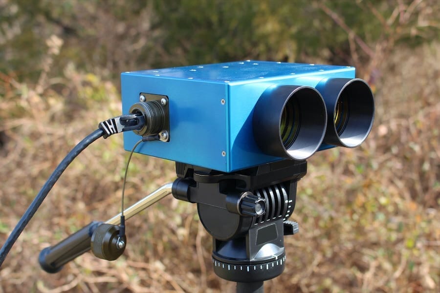 Blue optical sensor mounted on a tripod outdoors
