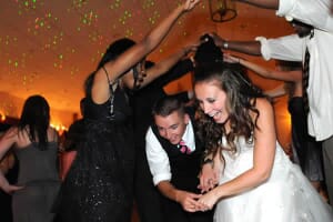 Bride and groom ducking under arms on dance floor