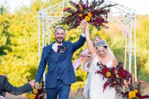 Couple raising their arms after an outdoor Maine wedding ceremony