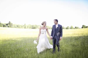 Bride and groom walking through a meadow