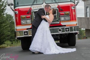 Bride and groom kissing in front of a firetruck