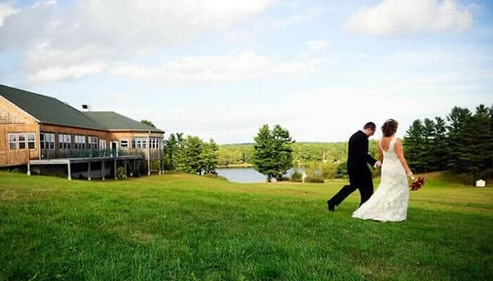Maine bride and groom walking in grass on Spring Hill grounds