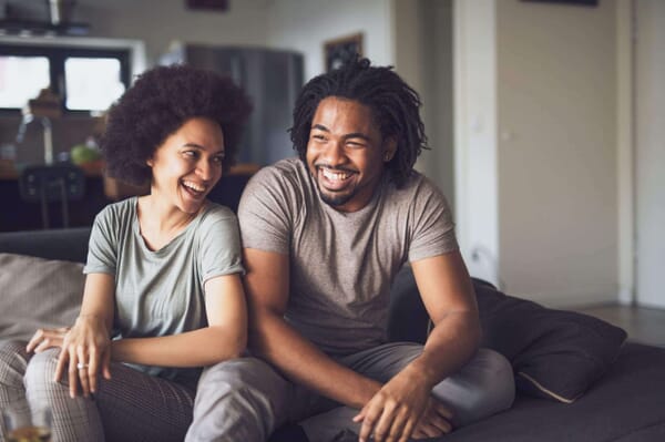 Smiling young black couple sitting on couch